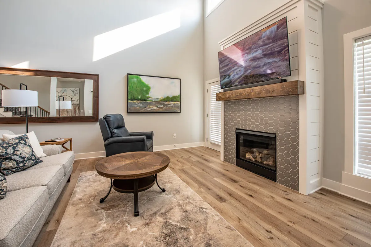 A comfortable living area centered around a plush sofa, coffee table, fireplace, TV, and vibrant artwork. The room is designed for relaxation, with ample seating for movie or game nights, and a cozy ambiance enhanced by the fireplace.