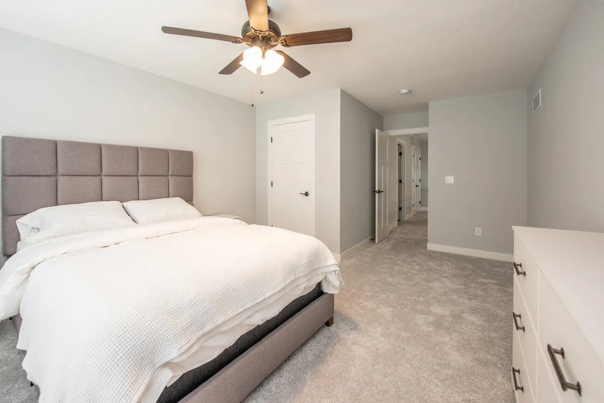 A tranquil bedroom with a clear view through a wide doorway into the adjacent hallway, highlighting broad transitions and open passageways. The layout showcases the seamless flow from one room to another, free from tight spaces or barriers.