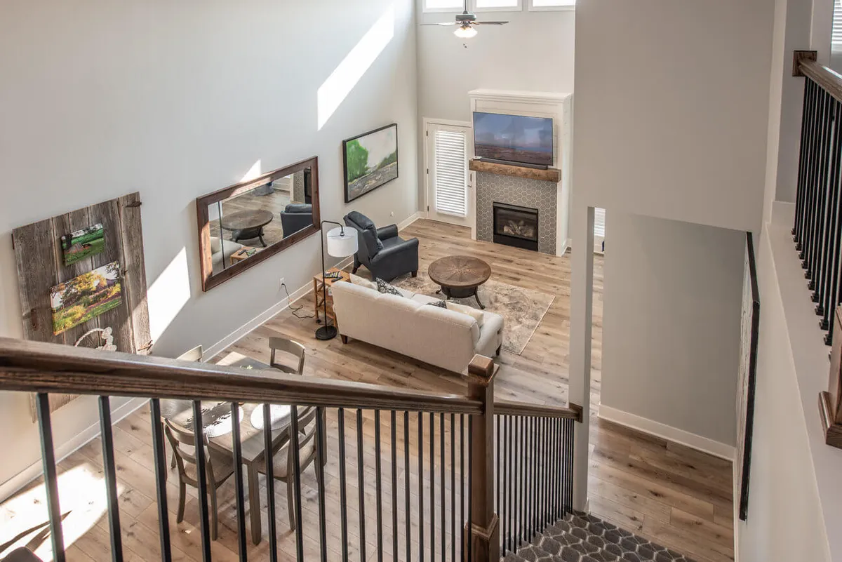 A bright, spacious living room featuring a plush sofa, coffee table, fireplace, large windows that flood the area with natural light, and curated artwork. The open layout encourages easy movement and invites family gatherings or relaxed afternoons spent reading by the window.