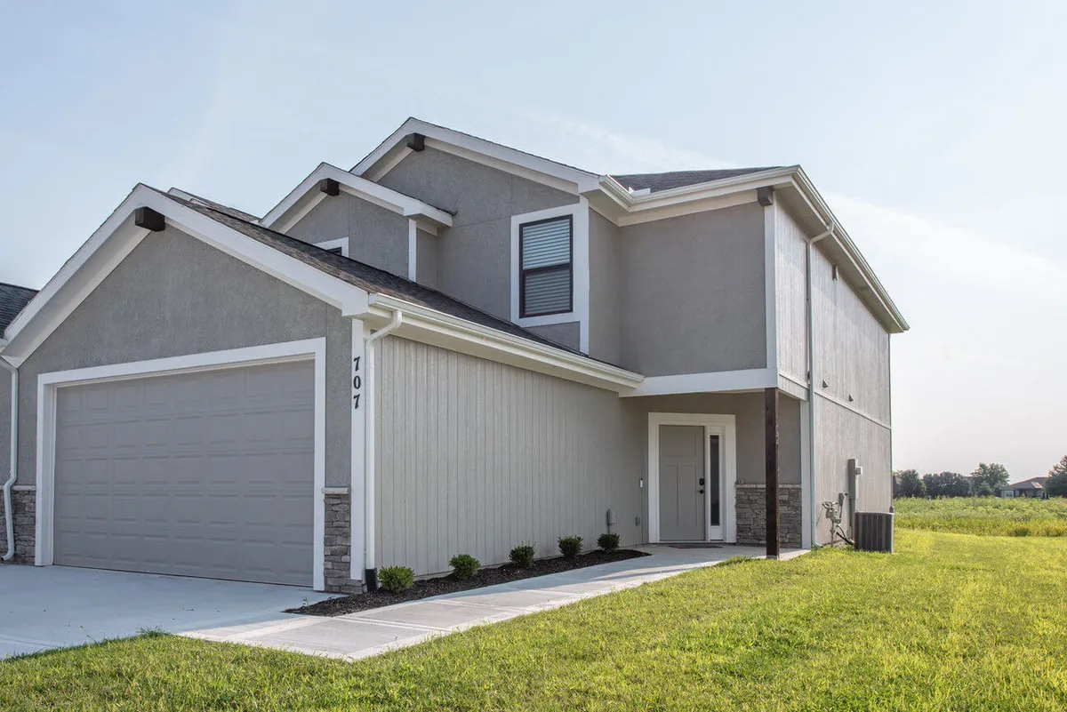 A welcoming exterior view showcasing the front entrance, garage door, and a landscaped pathway leading up to the home. The manicured greenery and clean lines offer a sense of approachability and connection to the outside world.
